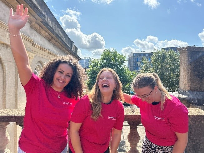 Three women laughing in Women's Aid t-shirts.