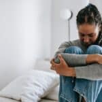 Woman sitting on a bed with her head down