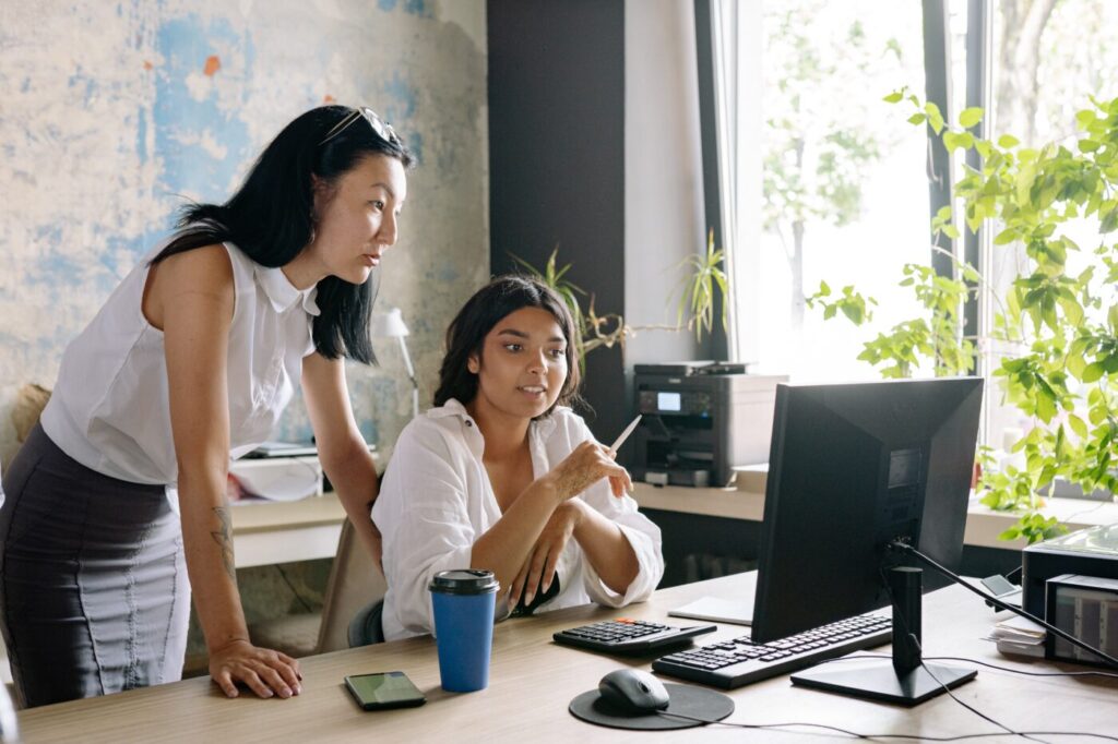 Two women at a desk looking at a computer screen