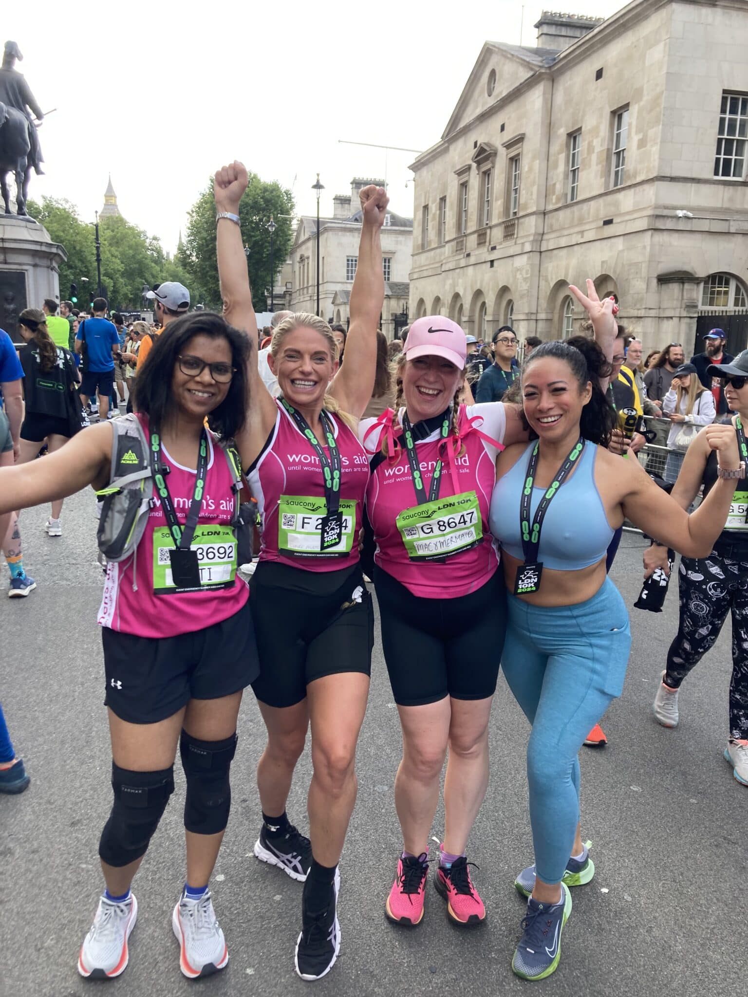 Four women smiling taking part in a charity run in a Women's Aid vest.