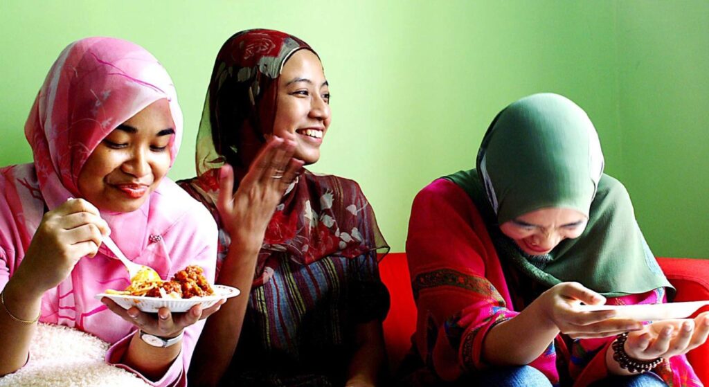 Women sitting together eating food laughing and smiling