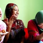 Group of women smiling with each other and eating food