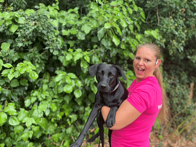 Woman in pink Women's Aid t-shirt holding black dog